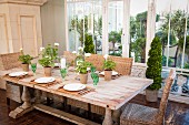 Set wooden table, wicker chairs, green crystal glasses and geraniums
