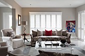 Various upholstered seating, louvre blinds and plexiglas coffee table in classic living room