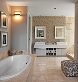 Elegant bathroom with large stone tiles, oval bathtub and twin washstand