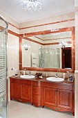 Massgefertigter Waschtisch aus Mahagoniholz vor gerahmtem Spiegel aus rötlichem Marmor, in traditionellem Bad mit modernem Flair