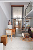 Offener moderner Wohnbereich mit Wendeltreppe zur Galerie, Retro Holzschaukelpferd und Blick durch Verglasung in hohe Diele und Küche