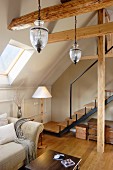 Pendant lamps above sofa in converted attic room with stairs leading to gallery in background