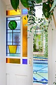 Open sliding door with stained glass panels and view of indoor pool