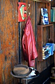 DIY coat peg made from books and hook next to bookshelves on rustic wooden wall