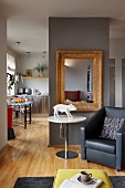 Leather armchair, pig sculpture on round table and antique mirror on partition screen kitchen-dining room in background