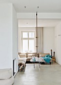 Modern interior with comfortable corner sofa below window and climbing rope hanging from ceiling
