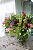 Luxuriant bouquet of lupins in glass vase and vintage metal bells on rustic wooden table