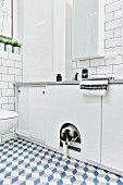 White bathroom with tiled walls & floor, wall-mounted cabinets & cat flap in sliding door of base unit