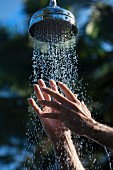 Man's hands in water falling from beach shower