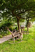 Vintage rocking chair under tree in idyllic garden
