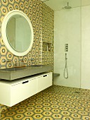 Washstand, round mirror, floor-level shower with glass screen in bathroom with retro tiles on wall and floor