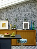Black counter, fifties-style pale-wood sideboard and wallpaper with retro pattern