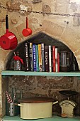 Cookery books and vintage kitchen utensils on shelf in niche with ogee arch