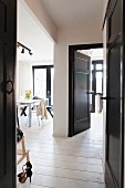 Open, black-painted interior door with view of dining area in black and white interior