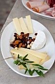 Plate of cheese and mixed nuts decorated with olive sprig