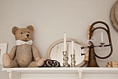 Teddy bear and silver candlesticks in front of mirror next to vintage bugle