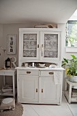 White dresser with lace curtains behind glass door panels