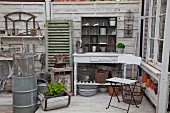 White folding chair and rustic console table with plant pots on lower shelf in shed