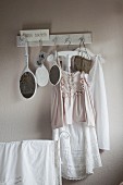 Vintage clothing and hand mirrors hanging from row of hooks