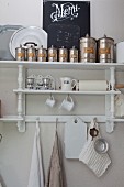 Metal storage tins on top of white-painted shelves