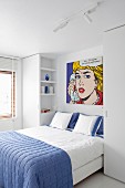 Doppelbett mit blauer Tagesdecke, darüber Pop-Art Kunstdruck, Roy Lichtenstein, in modernem Schlafzimmer in Weiß