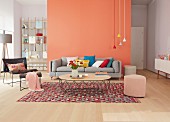A seating area with basic furniture, brightly coloured pendant lamps against a light red wall and complementary accessories