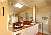 Designer bathroom - fitted washstand with white base units, large mirror and glass shower cubicle