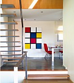 View from staircase of dining area with Piet Mondrian-style artwork on wall in modern, open-plan interior