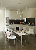 Crystal chandelier above modern dining set in black and white fitted kitchen