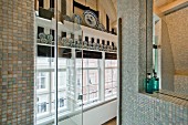 Duschkabine mit Glastür und Mosaikfliesen; Blick auf Giebelfenster und blau-weiße Wandteller