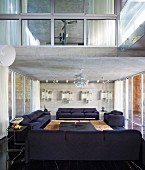 Dark sofa set below exposed concrete ceiling with classic pendant lamp in modern interior with view of room in upper storey