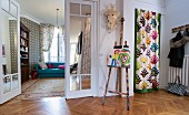 Colourful curtain screening niche in foyer, easel, double doors and view into living room