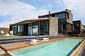 Spanische Ferienappartements mit Natursteinfassade; Sonnendeck am Pool im Vordergrund