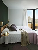 Double bed with pale blankets against dark accent wall in modern bedroom