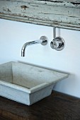 Rustic stone sink on wooden table below designer, wall-mounted tap