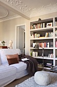 Seating area with bookcases, stucco ceiling, pouffe and white sofa