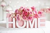 Pink roses in painted fruit crate and ornamental letters spelling 'HOME'