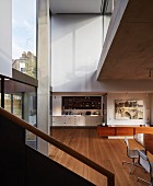 Blick vom Treppenaufgang in offenen Wohnraum, im Hintergrund Kochbereich in moderner Architektur
