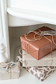 Stacked Christmas presents wrapped in gift paper in natural shades and tied with parcel string