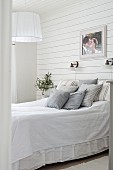 Scatter cushions on double bed in bedroom with wooden wall