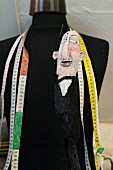 Tape measures and doll hanging on black tailors' dummy