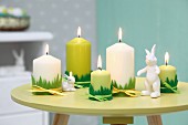 Easter arrangement in shades of green; candles with grass motif trim and rabbit ornaments on small, round table