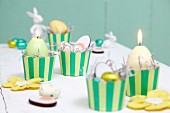 Easter arrangement in yellow and green; candles and sweets in stripe muffin cases