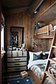 Bunk-beds in narrow children's bedroom in wooden house with vintage steamer trunk to one side