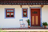 Ausschnitt eines alten, renovierten Bauernhauses mit blauen Faschen um Fenster und Tür