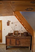 Rustic wooden trunk under staircase and painted wooden ceiling in hallway