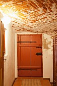 Cellar with rustic brick ceiling and brown board door with wrought iron fittings