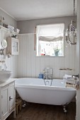 Vintage claw-foot bathtub against wood-clad wall in white bathroom