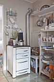 Old cooker and open-fronted shelves of crockery in vintage-style kitchen