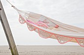 Hammock with crocheted trim hung on wooden posts